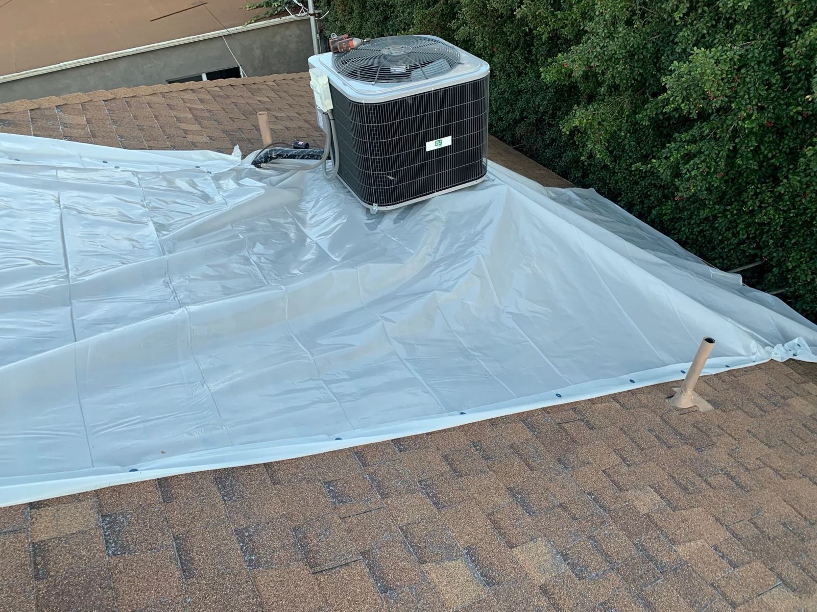 Emergency tarp secured around an AC unit